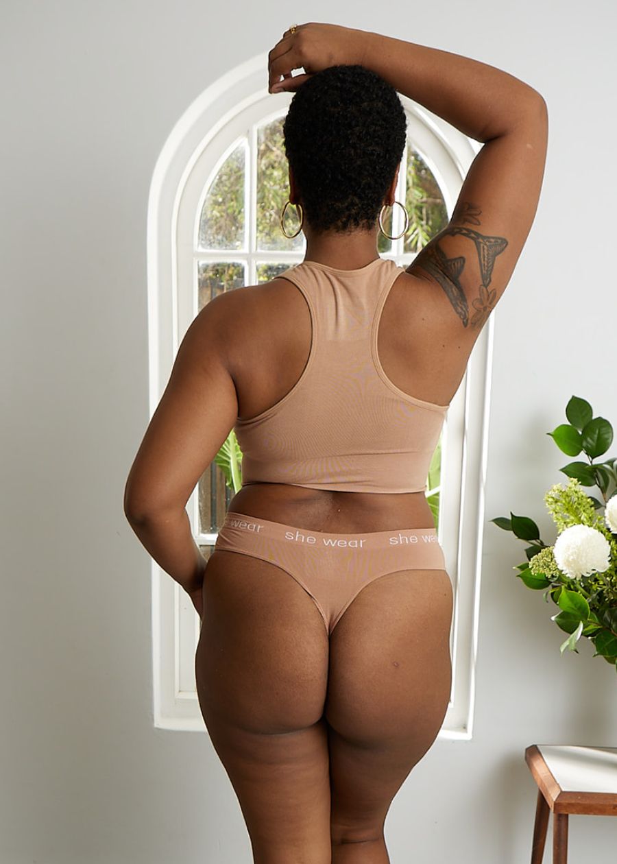 Rear view of woman in a comfortable beige racerback crop top bra and G-string made of stretchy organic bamboo.