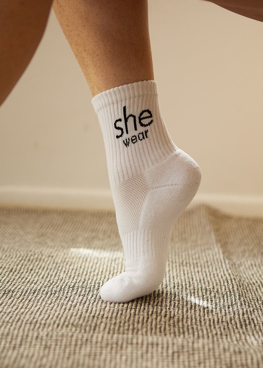 Woman's foot in white moisture-wicking padded performance sock. They're quarter crew length and designed in Australia.