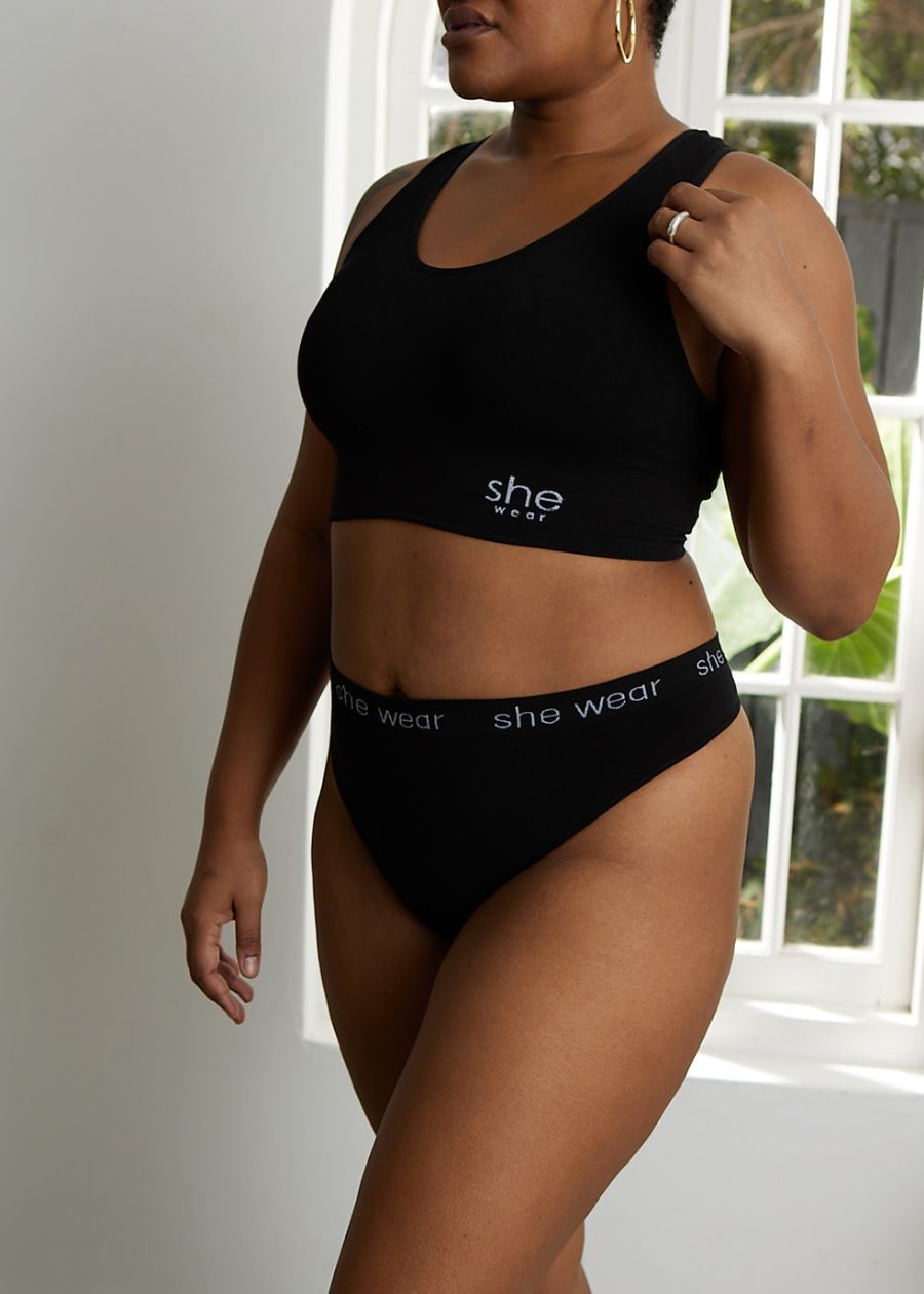 A woman wearing gold hoop earrings, a black full-coverage bra and black full coverage underwear