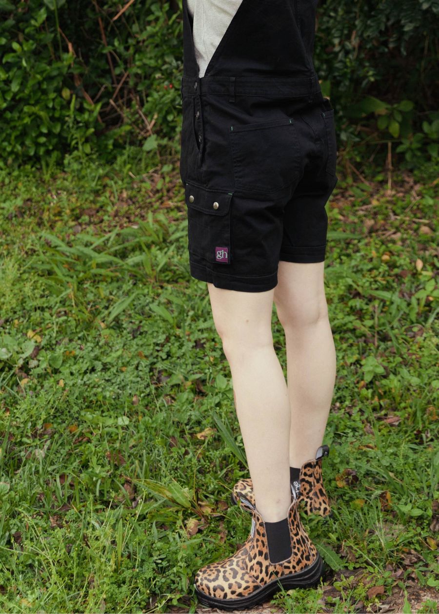 A woman wears black shortalls and leopard print pull-on boots